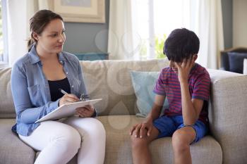 Young Boy With Problems Talking With Counselor At Home