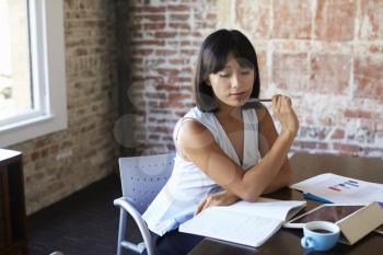 Businesswoman Making Notes On Document In Boardroom