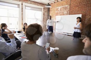 Businesspeople At Whiteboard Give Presentation In Boardroom