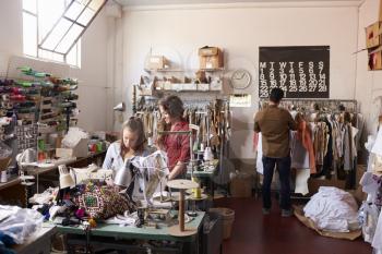 Colleagues working at a clothes design studio, full length