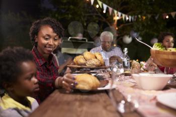 Young black mother serving her son food at a family barbecue