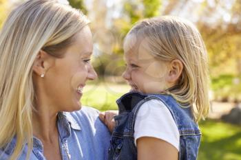 Blonde woman and young daughter look at each other, close up