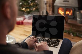 Man Using Laptop In Room Decorated For Christmas