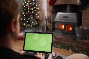 Man Using Laptop In Room Decorated For Christmas