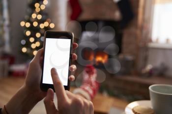 Man Using Mobile Phone In Room Decorated For Christmas