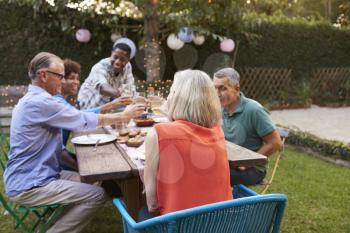 Group Of Mature Friends Enjoying Outdoor Meal In Backyard