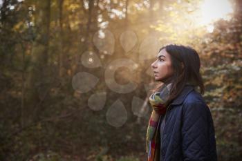 Woman Walks In Autumn Forest With Sun Shining Through Trees