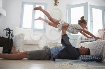 Father Lifting Daughter Into The Air Indoors