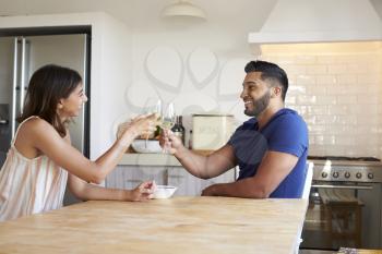 Adult couple drinking wine make a toast in the kitchen