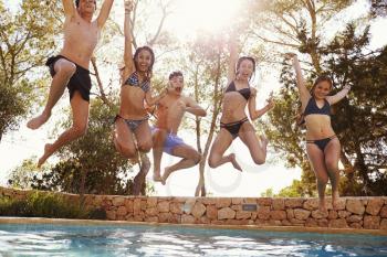 Teenagers jumping into an outdoor pool look to camera, Ibiza