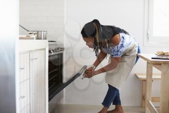 Woman bending down to look into the oven in her kitchen