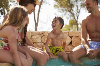 Family On Vacation Relaxing By Outdoor Pool