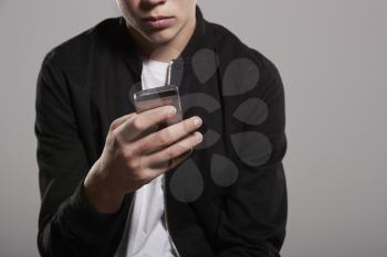 White teenage boy using mobile phone, mid section crop