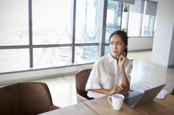 Businesswoman Working Alone On Laptop In Office Boardroom
