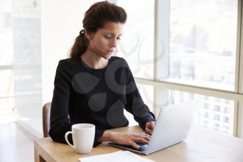 Businesswoman Working Alone On Laptop In Office Boardroom