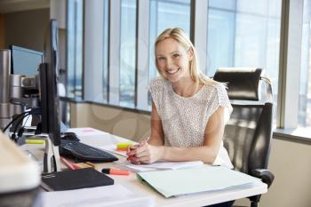 Portrait Of Businesswoman At Office Desk Using Computer