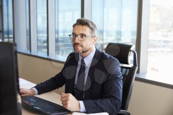 Businessman Sitting At Desk In Office Using Computer