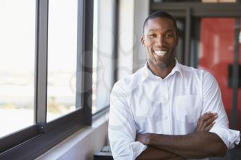 Young black man with arms crossed smiling, horizontal