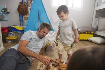 Father And Children Playing With Building Blocks In Bedroom