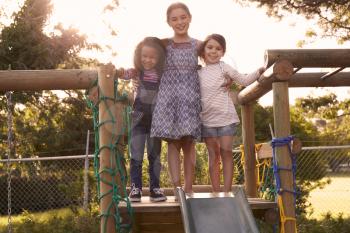 Three Girls Playing Outdoors At Home On Garden Slide