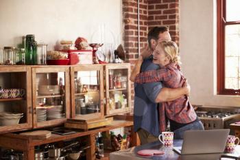 Young white couple hugging in their kitchen