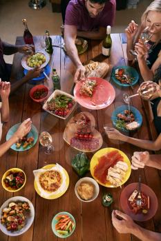 Overhead shot of friends passing food across a dinner table