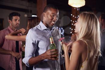 Black man and white woman talking at a party, side view