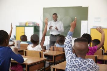 Kids raising hands during a lesson at an elementary school