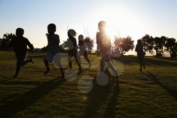 Silhouetted elementary school kids running in a field