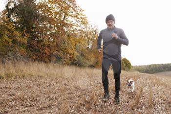 Mature Man Running Around Autumn Field With Pet Bulldog