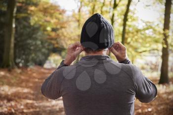Rear View Of Man Putting In Earphones Before Autumn Run