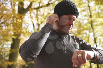 Man On Run Checking Activity Tracker And Putting In Earphones