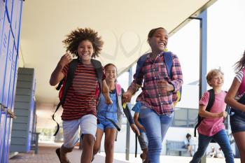 School kids running to camera in school hallway, close up