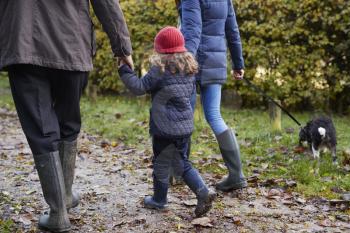 Multi Generation Family Take Dog For Walk In Fall Landscape