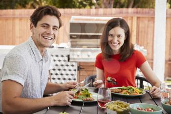 Young white couple eating in the garden looking to camera