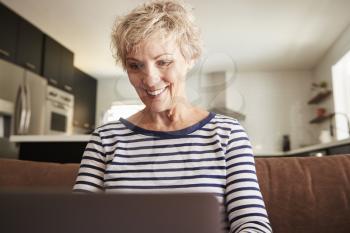 Senior white woman using laptop computer at home, close up