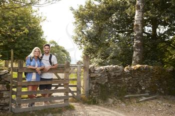 Portrait Of Couple Hiking In Lake District UK Looking Over Wooden Gate