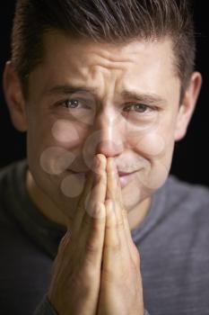 Close up of a worried young man with hands clasped, vertical