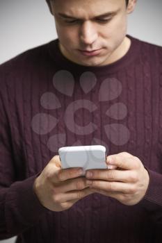 Vertical portrait of a young white man using a smartphone