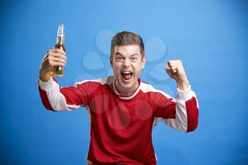 Portrait of cheering white male sports fan holding a bottle