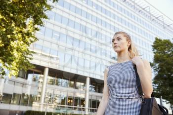 Businesswoman Walking Past Modern City Offices On Way To Work