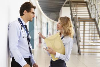 Young male and female doctors discuss notes at meeting