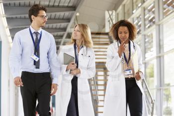 Three young male and female doctors walking in hospital