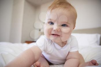 Happy Baby Boy Sitting On Parents Bed