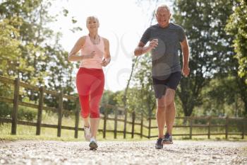 Healthy Senior Couple Enjoying Run Through Countryside Together