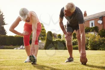 Healthy Senior Couple Exercising In Garden Together