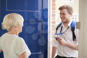 Senior woman opens door to male care worker showing his ID