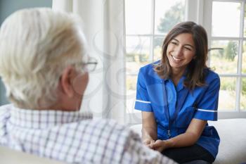 Over shoulder view of nurse on home visit with senior man