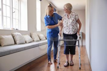 Nurse helping senior woman use a walking frame