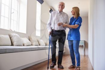 Nurse helping senior man walk using a walking stick